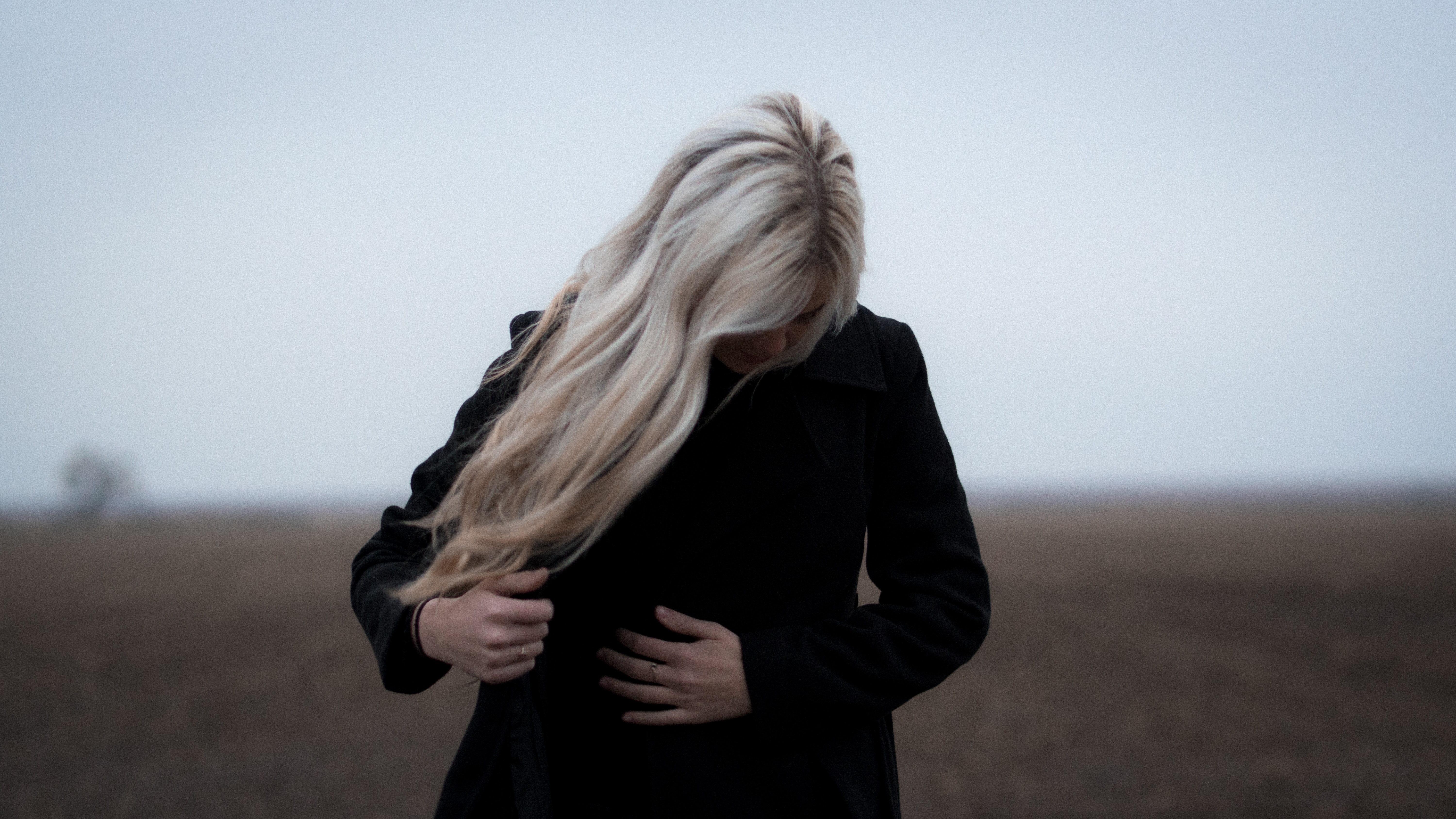 An image of a person with blonde hair standing in a field.