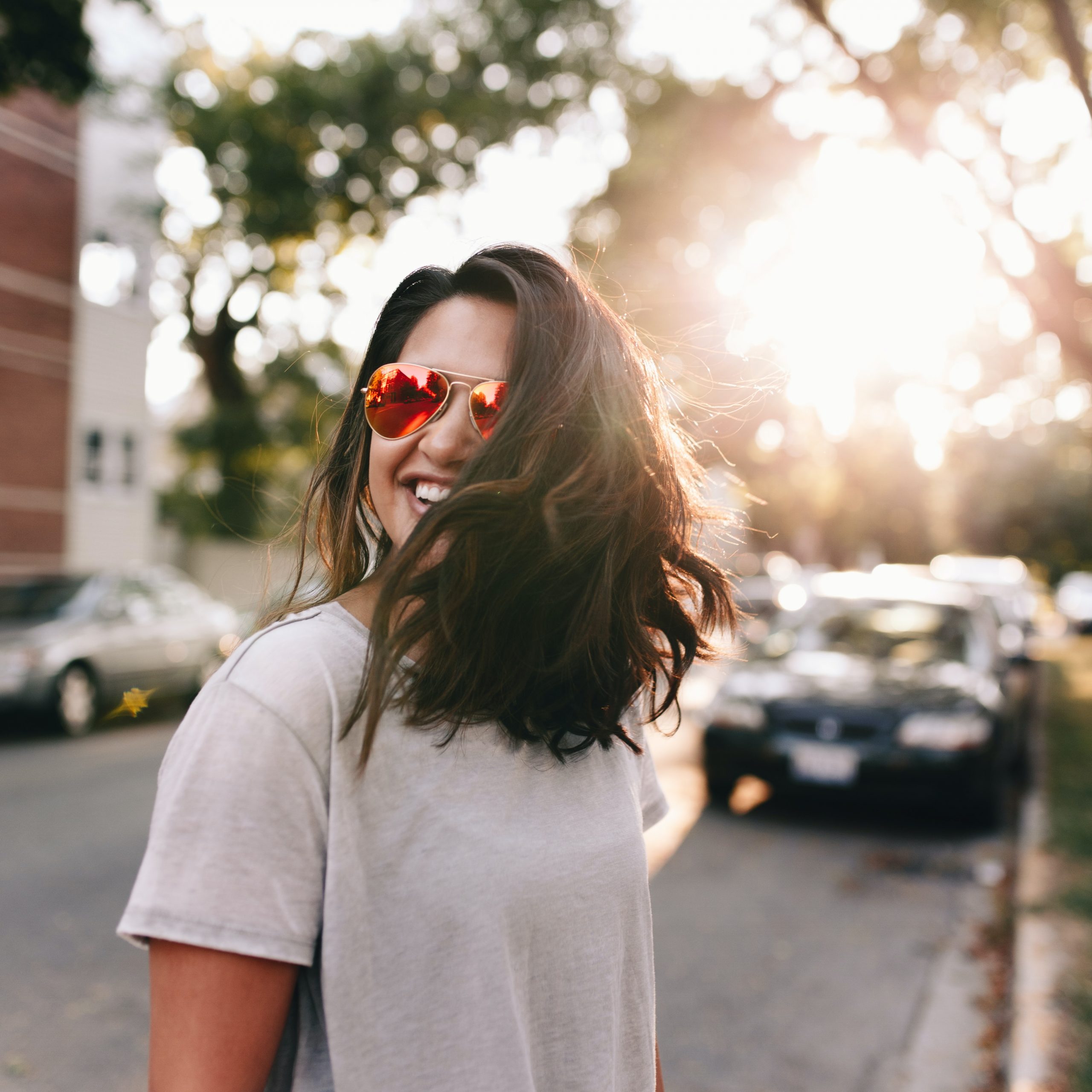 An image of a woman walking down the street with sunglasses on.